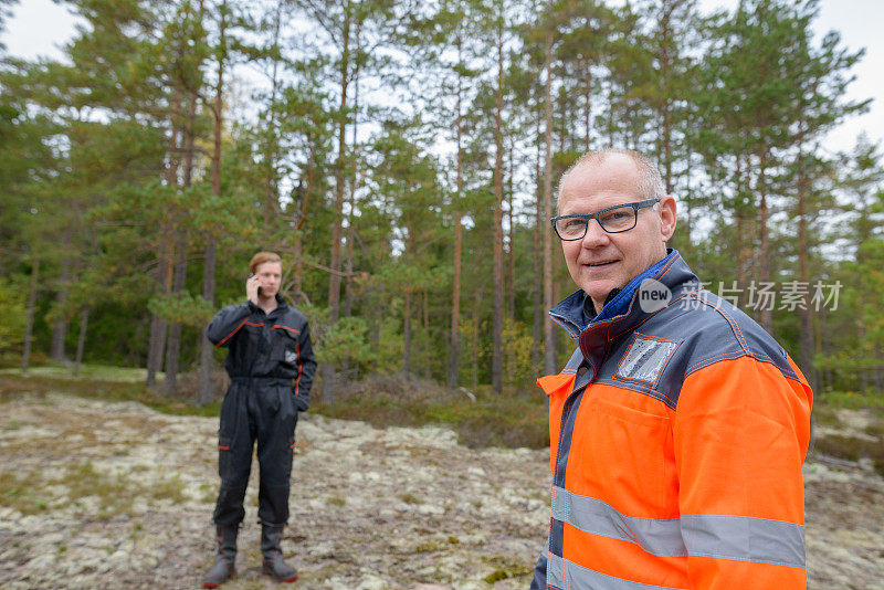 一个成熟的男人和一个年轻的男人一起在森林里工作