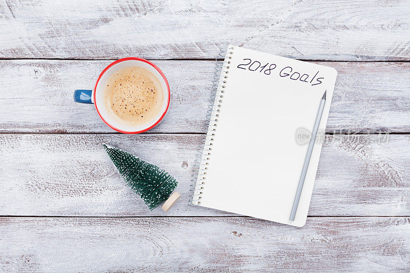 写着2018年目标的笔记本，木桌上的一杯咖啡。计划的概念。