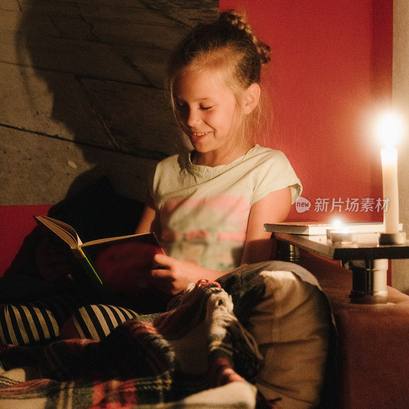 小女孩拿着蜡烛在床上看书