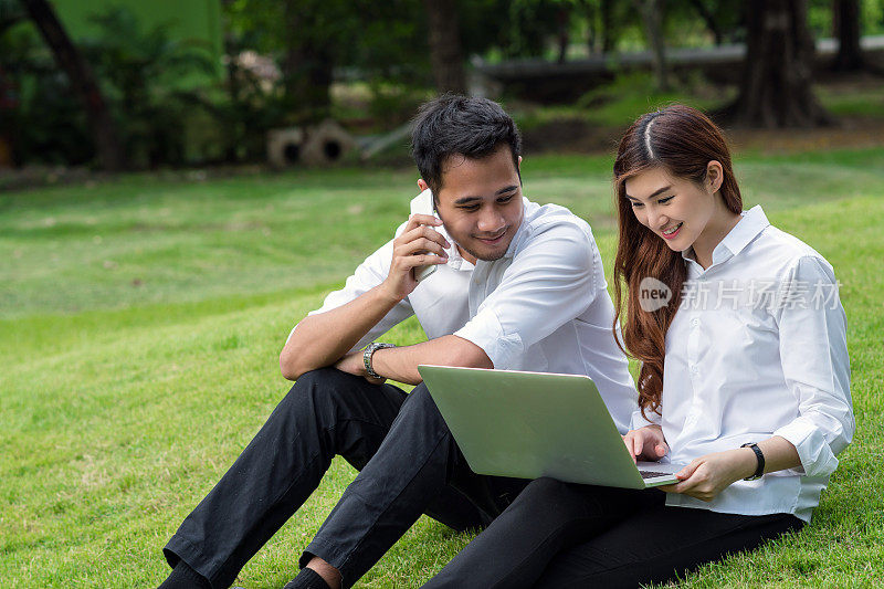 快乐的亚洲夫妇大学工作通过科技笔记本电脑在公园，商业和生活方式的概念