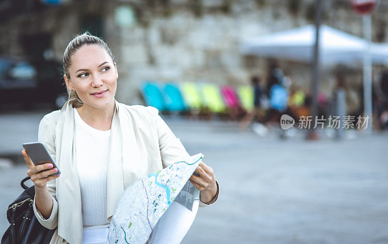 美丽的年轻女子在现实生活中旅行和使用地图