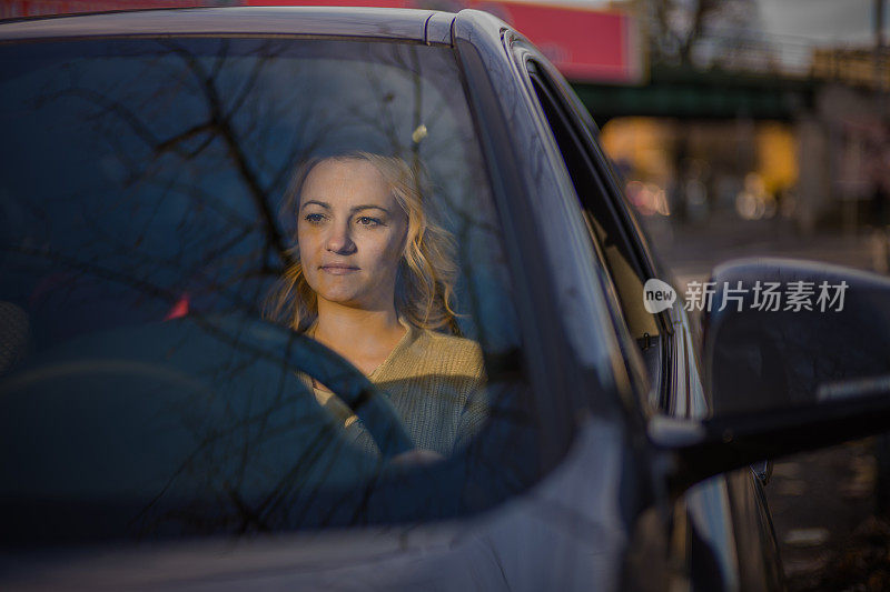 一个沉思的年轻女人在城里开车。