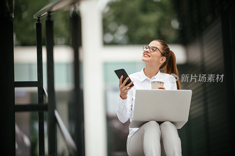 年轻漂亮的女商人一边打电话一边喝咖啡