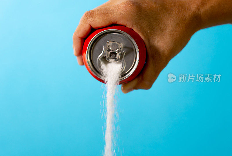在《营养饮食》中，手拿苏打水罐倾倒大量的糖，隐喻红色背景上隔离的清爽饮料的糖含量，不健康的食物成瘾和过量的卡路里含量。