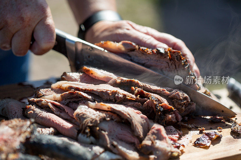 用切肉刀在木砧板上切热气腾腾的烤牛肉