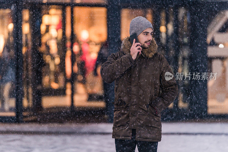 在一个下雪天，一个年轻人在参观城市购物中心后打电话。