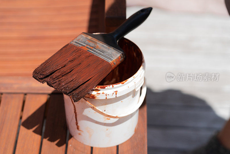 油漆刷和木材着色在一个塑料桶，用于外部房屋油漆