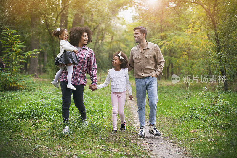 幸福的一家人在树林里的小路上散步