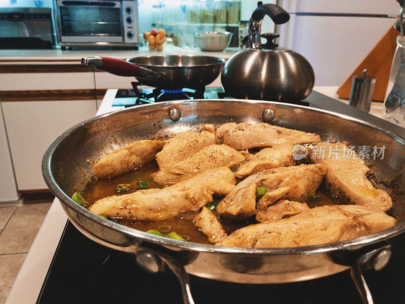 烹饪柠檬鸡类食物，在煤气炉上用不锈钢平底锅烹饪