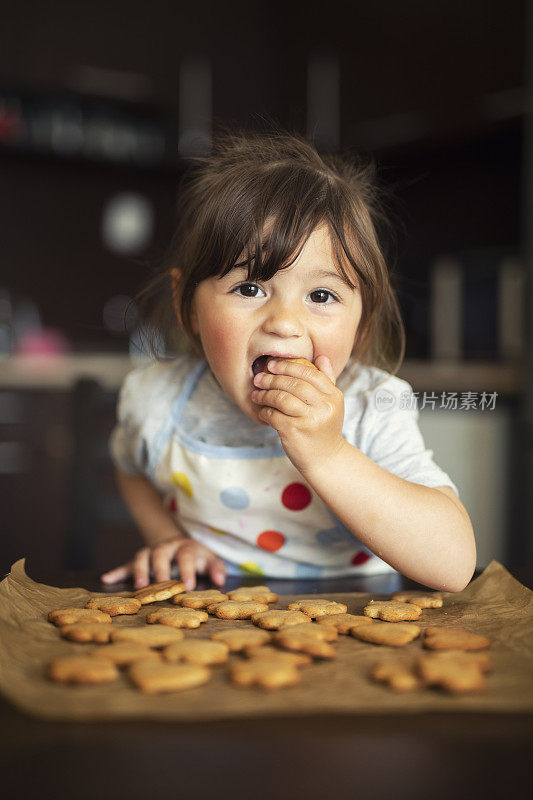 可爱的小女孩在厨房吃新鲜的饼干。