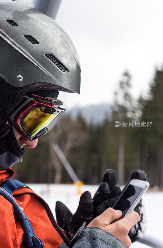滑雪者在滑雪缆车上使用智能手机。