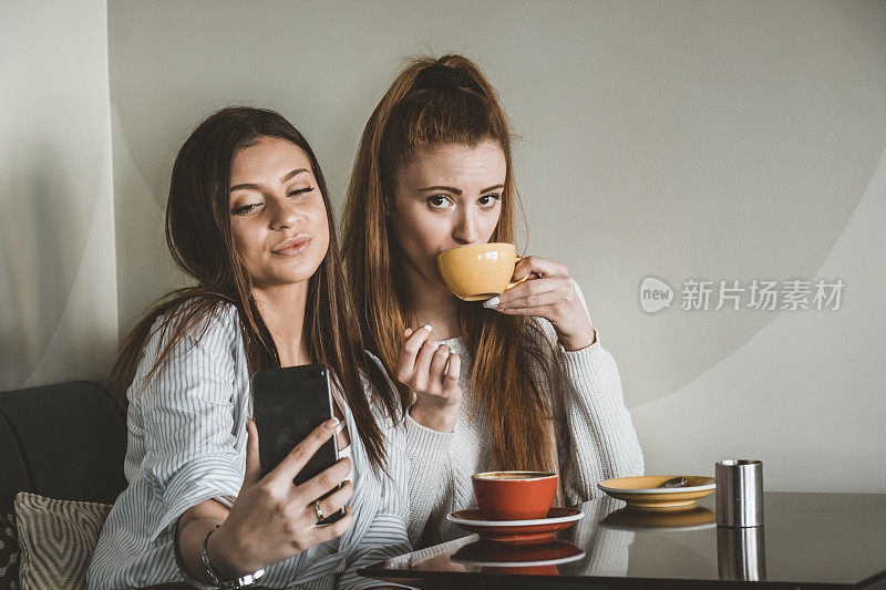 年轻的女性朋友们坐在咖啡馆里，拍下美丽的瞬间