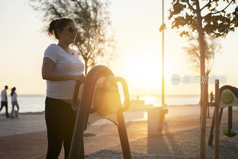 日落时分，孕妇带着健身器材。运动与健康的生活方式