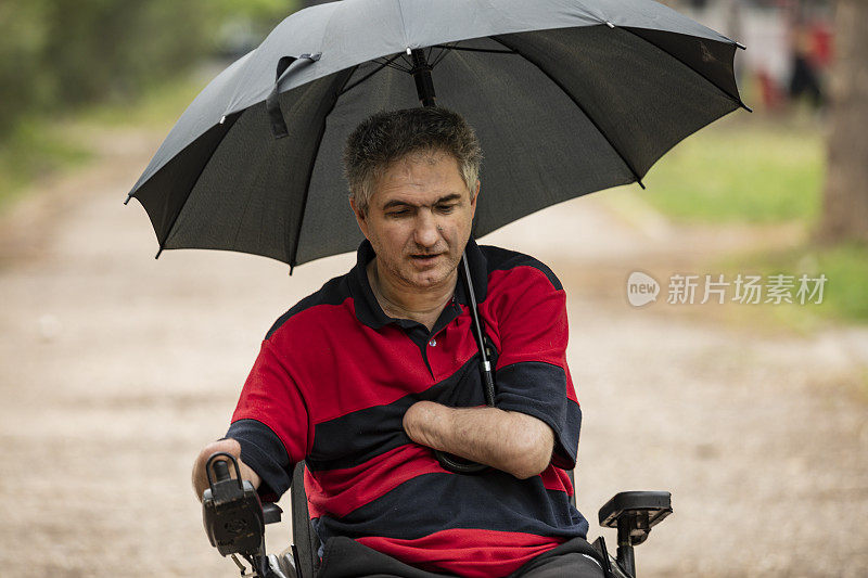 在雨天坐电动轮椅的残疾人在移动