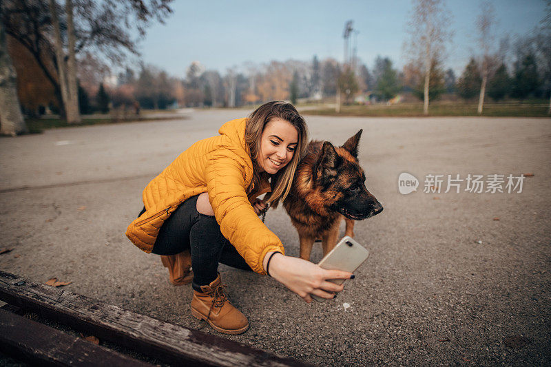 年轻女子正在和一只德国牧羊犬自拍