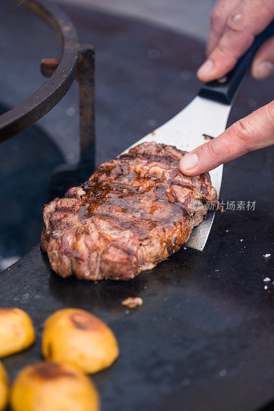 男人在烤肉架上用抹刀旋转牛肉