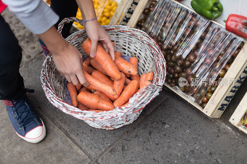 蔬菜水果店的售货员，手里拿着满满一篮子胡萝卜
