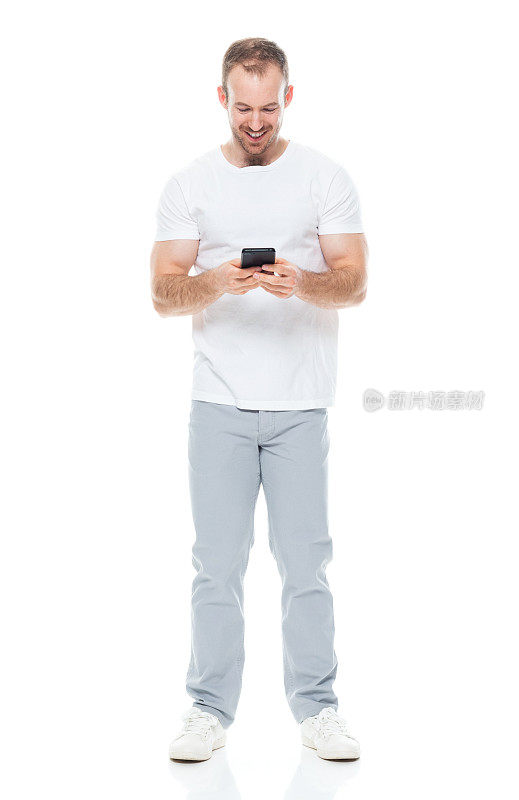 白人年轻男性穿着帆布鞋站在白色背景前使用手机