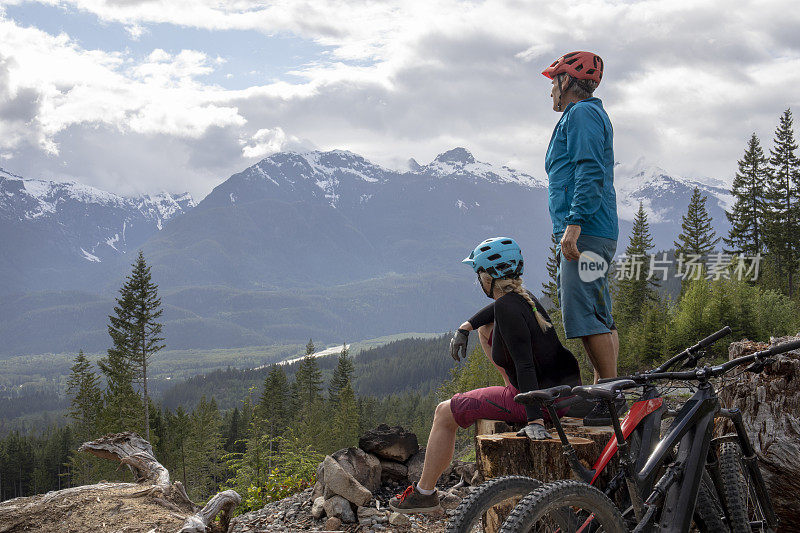 几个山地自行车手停下来欣赏高山、山谷和森林的景色