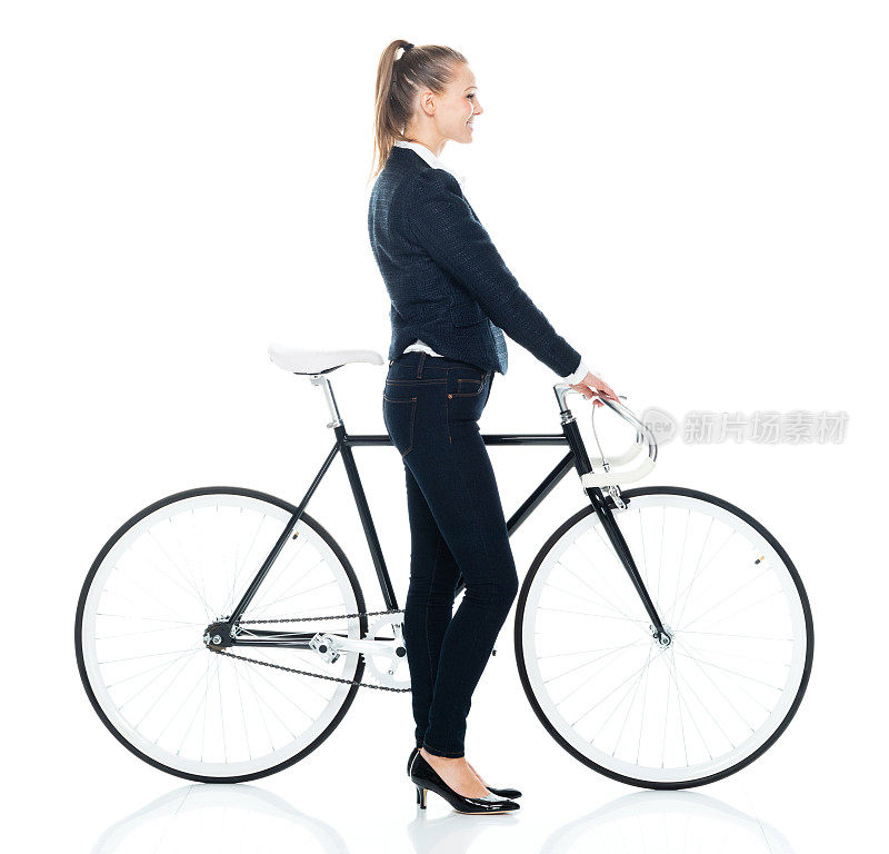 白人年轻女商人穿着商务休闲装，骑着自行车站在白色背景前
