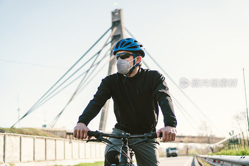 男性骑单车者戴上带有重型防护过滤器的防毒面具。骑自行车的人戴着带有重型防护过滤器的防毒面具。安全呼吸面具。污染的概念