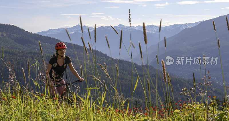 年轻女子骑山地车穿过山地草地