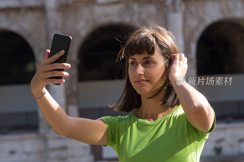 意大利罗马，一名年轻女子在用智能手机自拍