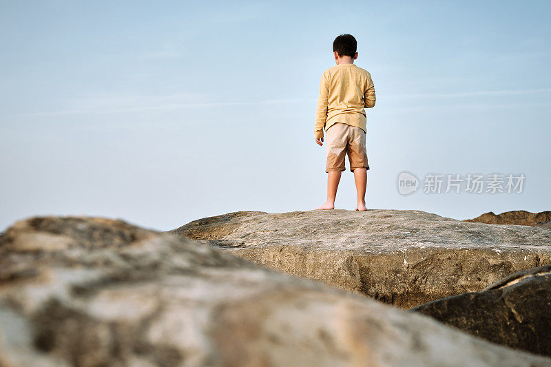 孩子看向海边的岩石