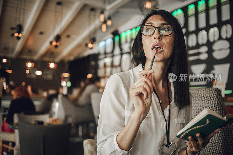 一个年老的女商人在咖啡店的咖啡休息-一个年老的女商人谁有白癜风在她的皮肤上