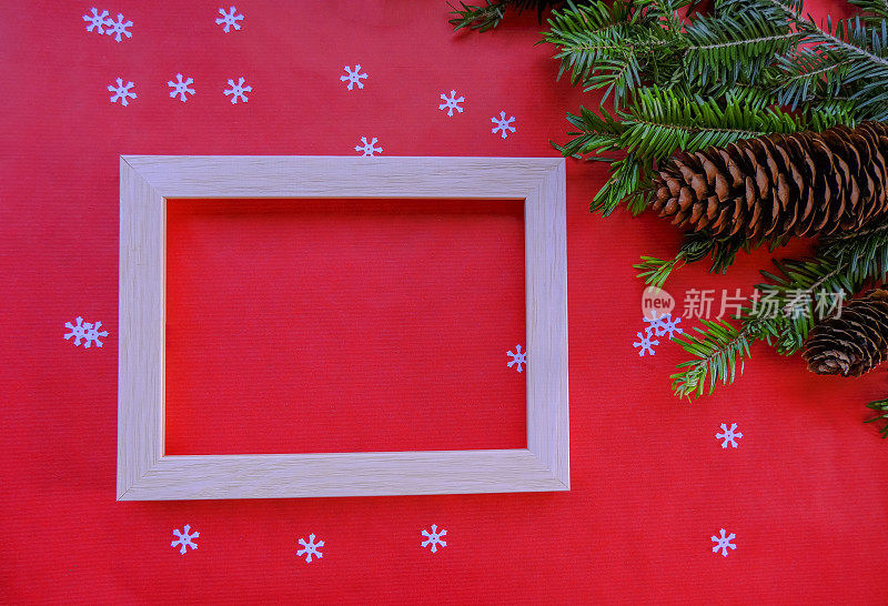 圣诞贺卡与画框横跨圣诞树的树枝，锥，金箔在红色的背景。前视图。本空间