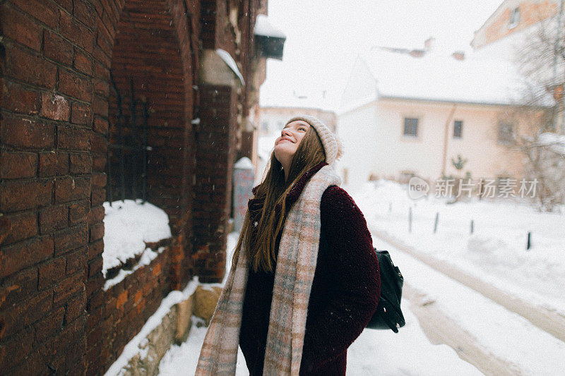 年轻女子抬头欣赏着飘落的雪花