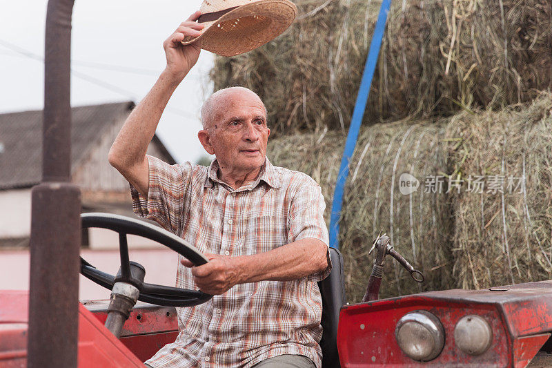 退休农民开着拖拉机，戴着草帽