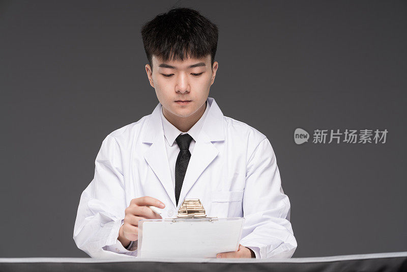 一位年轻的亚洲男医生坐在他的办公桌前