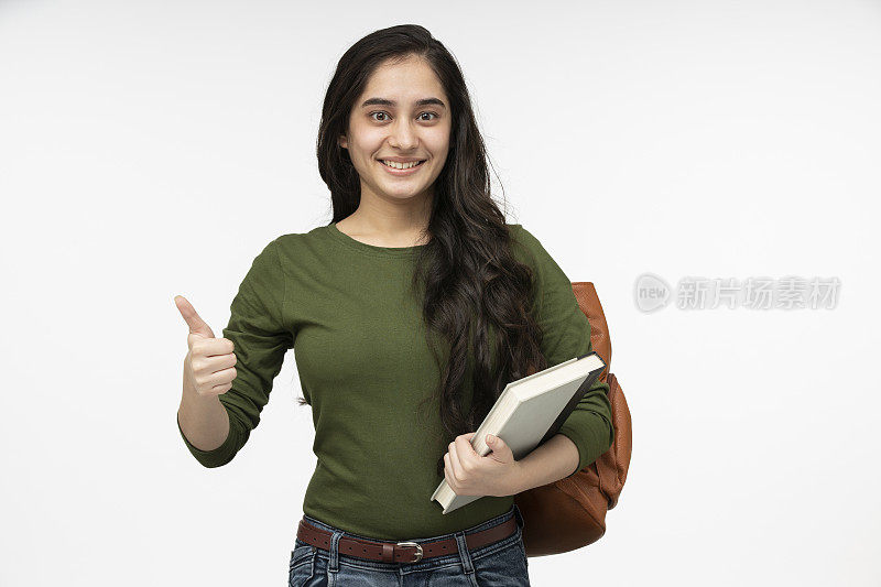 女十几岁的学生背着书包和书微笑的股票照片