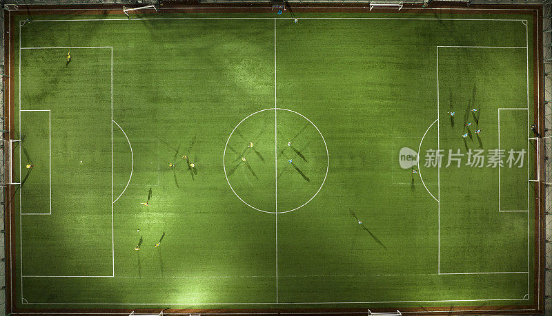 绿色足球场的鸟瞰图，难以辨认的小球员的轮廓;在户外。