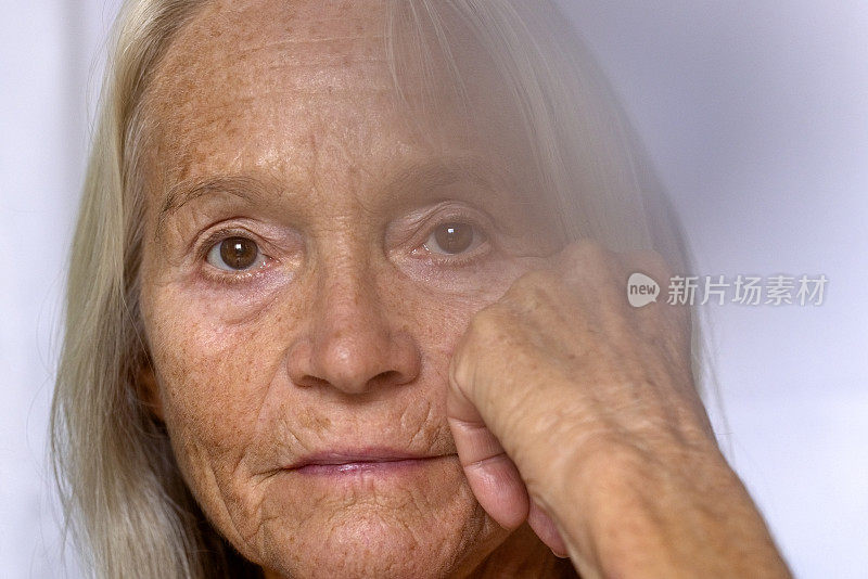 老年女人的特写肖像与手在下巴上，背景与复制空间