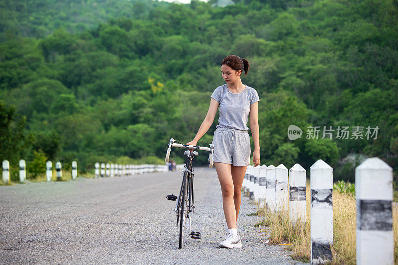 亚洲女孩骑自行车旅行山脊在夏天