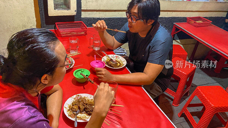 年轻的印尼男子吃沙爹鸡