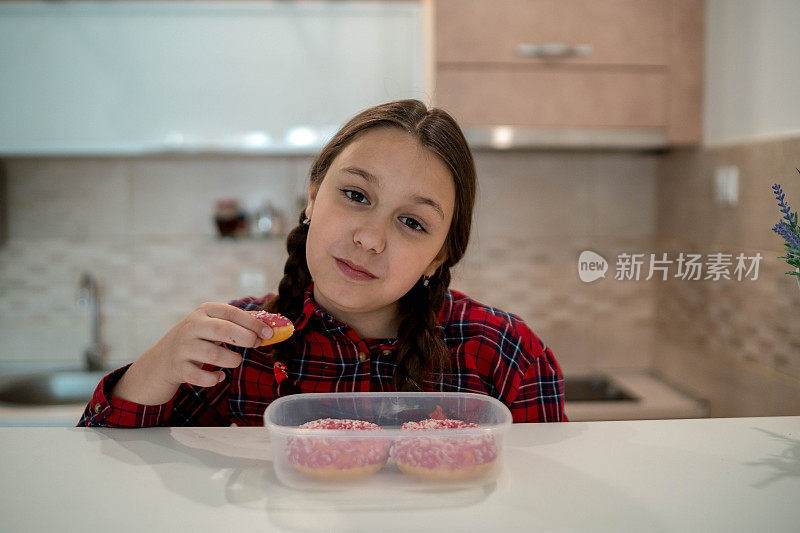 可爱的小女孩在吃粉色的甜甜圈