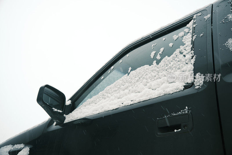 雪花飘落，盖住了汽车的一部分