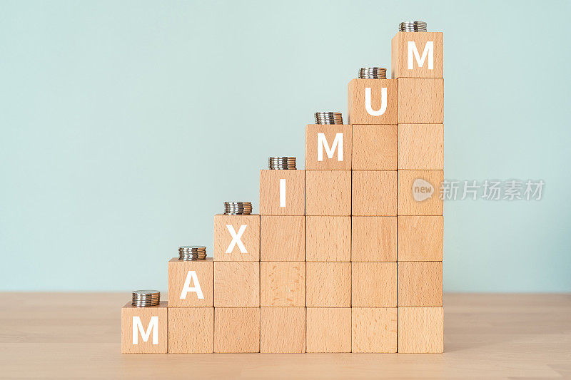木块与“MAXIMUM”文本的概念和硬币。