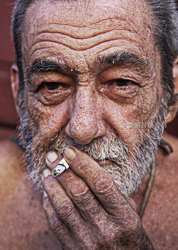 一个满脸皱纹的老男人抽烟的垂直画像