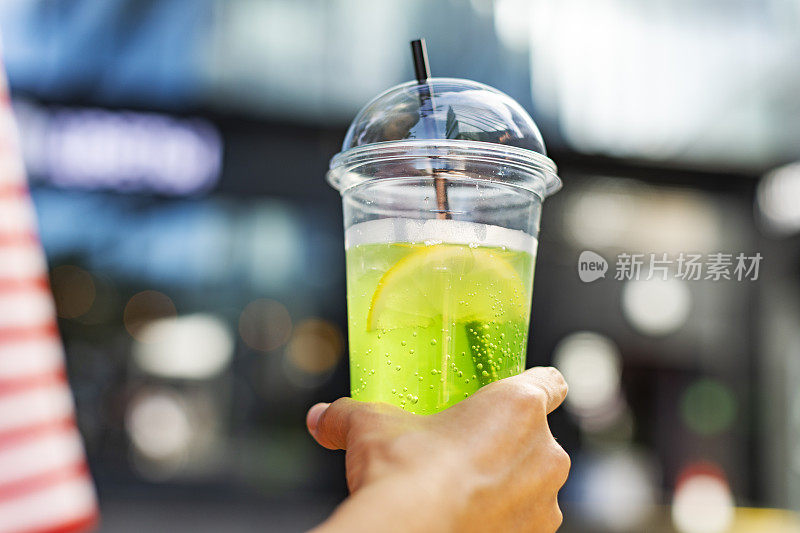 用塑料杯盛着柠檬水的女人的手