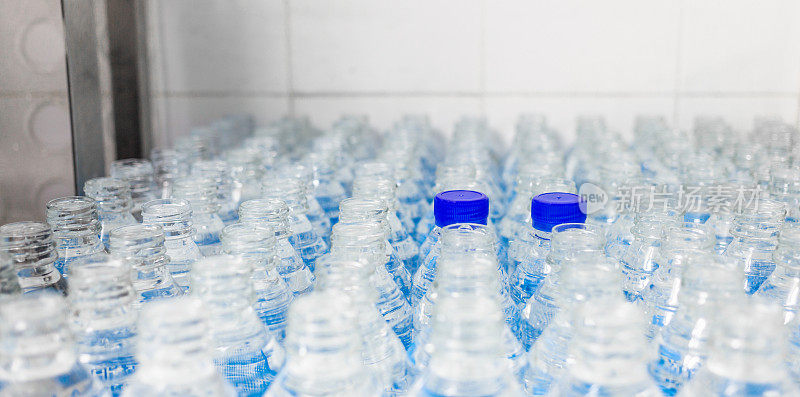 很多水瓶。蓝色瓶盖的瓶子。装瓶厂-水装瓶生产线，用于加工和装瓶饮用水。