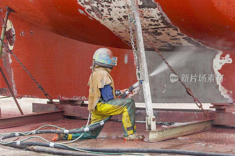 一名工人正在对锈蚀的船体进行喷砂处理