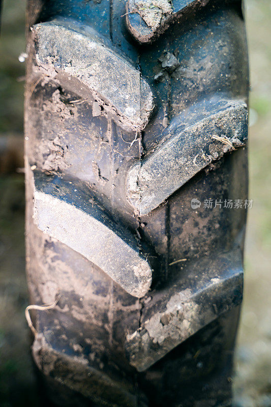 拖拉机车轮上的体积橡胶胎面特写。泥胎花纹对农机越野能力更强，垂直拍照