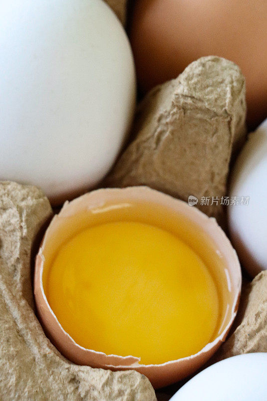 混合彩色鸡蛋的全帧图像，白色和棕色交替的壳，破碎的鸡蛋与蛋黄和蛋白的观点，抬高的观点