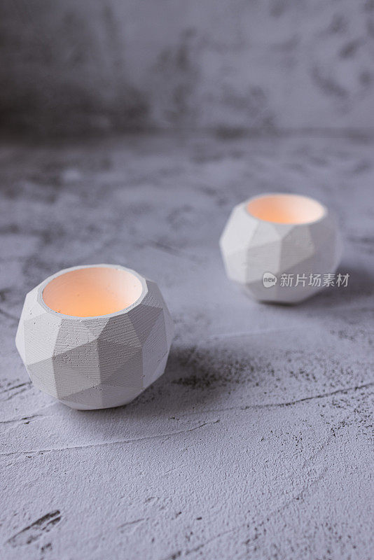 白色圆形石制烛台放在粗糙的浅灰色混凝土地板上