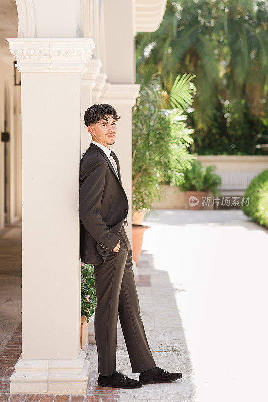 一位18岁的古巴裔美国人，穿着一身黑色西装，白色衬衫，黑色领带和黑色麂皮鞋，棕色头发和棕色眼睛，穿着西装和领带，在佛罗里达州棕榈滩的一个优雅的地方看起来清新而敏锐