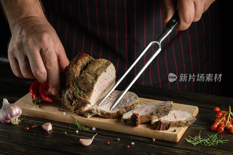 多汁的烤牛排。把肉切成薄片放在砧板上。叉子在厨师的手在黑暗的背景